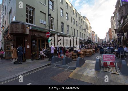 Menschen in einem Restaurant werden hinter einem Schild mit „vorübergehenden Zwangsbeschränkungen“ im Londoner Stadtteil Soho gesehen, das alle Einschränkungen des täglichen Lebens in England aufhebt. Stockfoto