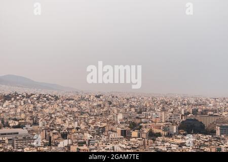 Im Stadtzentrum von Athen überfüllte Straßen mit weißer Architektur an bewölkten, nebligen Tagen. Blick vom Filopappou-Hügel in der Nähe der Akropolis, Griechenland Stockfoto