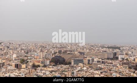 Das moderne Stadtzentrum Athens ist überfüllt mit weißen Gebäuden an bewölkten, nebligen Tagen. Blick vom Filopappou-Hügel in der Nähe der Akropolis, Stockfoto