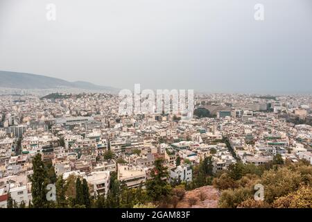 Moderne Straßen im Stadtzentrum von Athen mit weißen Gebäuden an bewölkten, nebligen Tagen. Blick auf die Attika vom Filopappou-Hügel in der Nähe der Akropolis, Griechenland Stockfoto