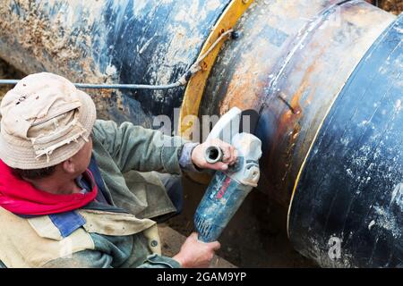 Odessa, Ukraine - 11. Oktober 2016: Reparatur des Heizkanals. Die Arbeiter, Schweißer, die durch Elektroschweißen und Gasschweißen an großen Eisenrohren bei einem Ableiter hergestellt wurden Stockfoto