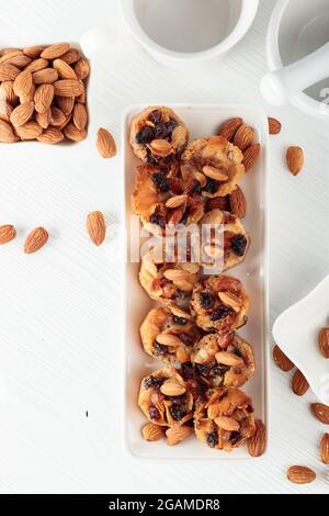 Kleine Kuchen mit Mandeln, Rosinen und Honig auf einem weißen Tisch. Stockfoto