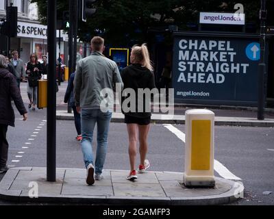 Pärchen, die auf Road Island vor dem Schild für Chapel Street Market in Islington London stehen Stockfoto