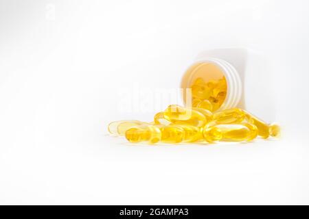 omega 3 Pillen, die aus dem Glas auf weißem Hintergrund ausgegossen werden Stockfoto