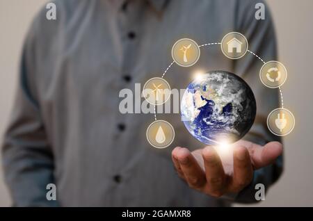 Nahaufnahme der Mensch, der den Planeten Erde als grün und trocken hält. Konzept für erneuerbare Energien und ökologische Biodiversität. Elemente dieses Bildes furniss Stockfoto
