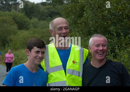 Sa 31 Jul 2021 Adrigole, West Cork Irland. Familie und Freunde des tragischen Unfallopfers Tadgh Murphy veranstalteten eine Gedenkwanderung zur Unterstützung der Rapid Response Air Ambulance der irischen Gemeinschaft. Tagdh, 19, starb, nachdem das Auto, in dem er fuhr, zusammen mit einem anderen Mann, Michael Bowen (40), in einen Fluss auf der Glengarriff-Kenmare-Straße gefahren war. 2 andere Männer überlebten den Absturz. Derven Harrington, Tadghs Cousin aus Washington DC, Denis O'Sullivan, Glengarriff und Johnny Harrington, Tadghs Onkel, der am Vortag aus Washington DC angereist war, machen eine kurze Wasserpause. Credit ED/Alamy Live News Stockfoto