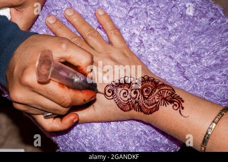 Henna-Künstler, der Henna auf die Hand gibt. Stockfoto
