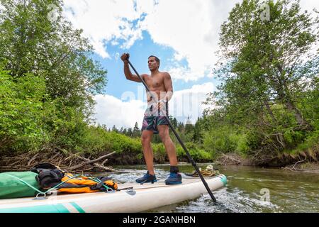 Abenteuerliche hispanische Erwachsene Athletic man Paddle Boarding Stockfoto