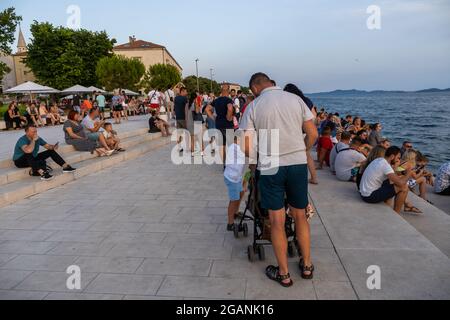 ZADAR, KROATIEN - 21. Jul 2021: Nahaufnahme von Menschen, die am Abend ein ankommendes Taxiboot in Zadar, Kroatien, beobachten Stockfoto