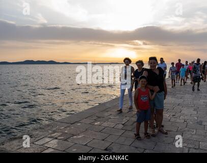 ZADAR, KROATIEN - 21. Jul 2021: Nahaufnahme vieler Menschen, die den Sonnenuntergang am Meer in Kroatien beobachten Stockfoto