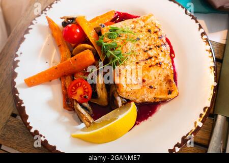 Ein Gericht aus gegrilltem Lachsfilet mit Gemüse auf einem Teller Stockfoto