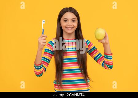 Mundhygiene beachten. Glückliches Mädchen halten Apfel und Zahnbürste. Mundhygiene. Zahnpflege Stockfoto