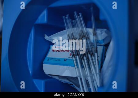 Ein Trägergefriergerät mit Dosen und Spritzen des Impfstoffes Moderna COVID-19, wenn die Menschen am 29. Juli 2021 in Yumbo - Cali - Valle del Cauca die erste Dosis des neuartigen Coronavirus-Impfstoffes von Moderna erhalten. Stockfoto