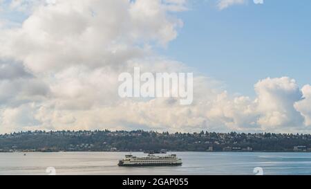 Washington Ferry fährt auf Elliot Bay mit West Seattle und Wolkenhimmel Hintergrund Stockfoto