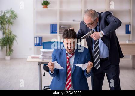 Alter Chef und junger Mitarbeiter im Mobbing-Konzept Stockfoto