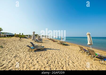 Tolle Aussicht auf die Landschaft mit leeren Sonnenliegen und Sonnenschirmen am Sandstrand. Griechenland. Stockfoto