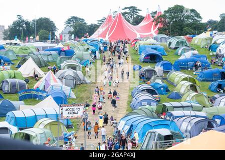 Lulworth, Dorset UK, Samstag, 31. Juli 2021 Festivalbesucher wandern am 2. Tag des Camp Beestival, Lulworth Castle, Dorset, einen Hügel hinauf durch einen Campingplatz auf ihrem Weg zur Hauptarena. Kredit: DavidJensen / Empics Unterhaltung / Alamy Live Nachrichten Stockfoto