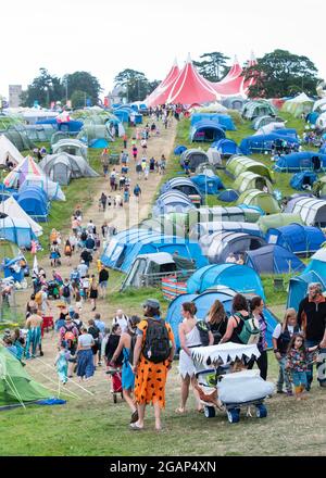 Lulworth, Dorset UK, Samstag, 31. Juli 2021 Festivalbesucher wandern am 2. Tag des Camp Beestival, Lulworth Castle, Dorset, einen Hügel hinauf durch einen Campingplatz auf ihrem Weg zur Hauptarena. Kredit: DavidJensen / Empics Unterhaltung / Alamy Live Nachrichten Stockfoto