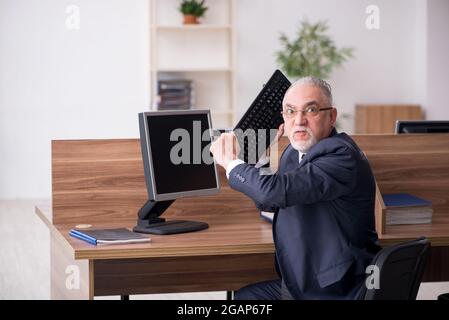 Gealterter Geschäftsmann, der am Arbeitsplatz sitzt Stockfoto