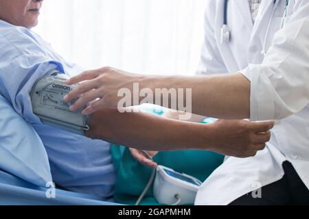 Nahaufnahme des Arztes, der im Krankenhaus arbeitet und das Blutdruckmessgerät an der Hand eines älteren Mannes anpasst Stockfoto