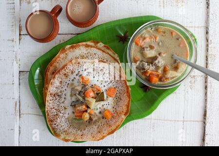 Appam, Hoppers und Hammelfleisch Eintopf Kerala Frühstück Essen und indische Milch Tee Chai, christian Frühstück Indien Sri Lanka Tamil Nadu fermentierten Reis Pfanne Kuchen. Stockfoto