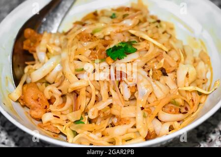 Myanmar traditioneller oder klassischer weißer flacher Nudelsalat namens Khauk SWE Thoke in weißer Schale. Nahaufnahme. Stockfoto