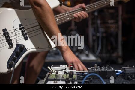 Ein männlicher Gitarrist, der auf der Bühne Audio-Verarbeitungseffekte für die Gitarre einspielt. Stockfoto