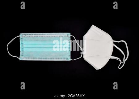 Einweg-KN-95-Maske im Vergleich zu dünner OP-Maske. COVID-19-Prävention. H1N1-, H5N1-Sicherheitsmaßnahmen. Isoliert auf schwarzem Hintergrund. Stockfoto