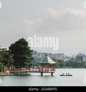 Fukuoka, Japan - EIN Boot und ein sechseckiger, verzinnter Pavillon auf einem großen Teich im Ohori Park oder Ōhori-kōen, einem angenehmen Stadtpark im Zentrum von Fukuoka. Stockfoto