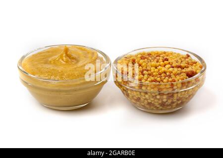 Senfgelbe Sauce in einer klaren Schüssel und eingelegte Senfkörner isoliert auf weißem Hintergrund. Stockfoto