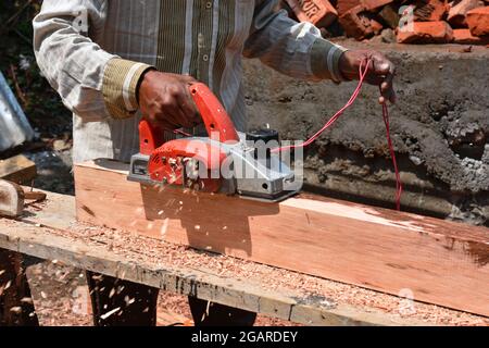 Elektrische Holzhobelmaschine, Mann bei der Arbeit mit Holz und Maschine. Stockfoto