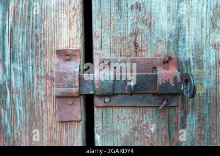 Altes Eisen, rostiger Riegel am alten Holztor. Verriegelte Tür. Stockfoto