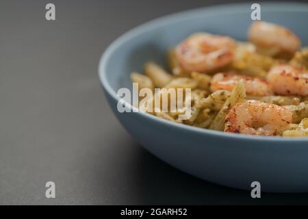 Penne-Pasta mit Garnelen und Pesto in blauer Schale mit Kopierfläche, flacher Fokus Stockfoto