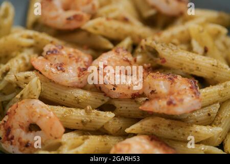 Penne mit Garnelen und Pesto in blauer Schale, flacher Fokus Stockfoto