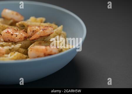 Penne-Pasta mit Garnelen und Pesto in blauer Schale mit Kopierfläche, flacher Fokus Stockfoto