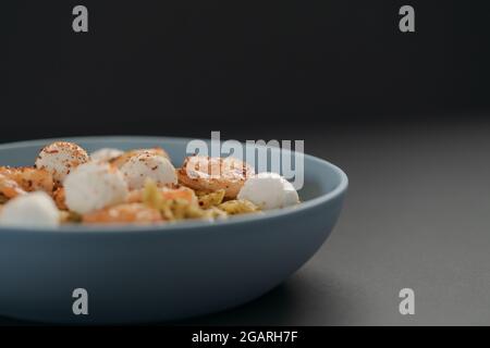 Penne-Pasta mit Garnelen und Mozzarella und Pesto in blauer Schale mit Kopierfläche, flacher Fokus Stockfoto