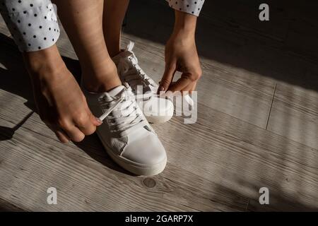 Frau zog neue weiße Leder-Sneakers an Stockfoto