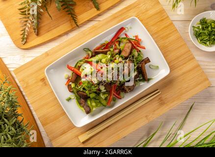 Flacher Salat im asiatischen Stil mit Rinderwürfeln, verziert mit Sprossen Stockfoto