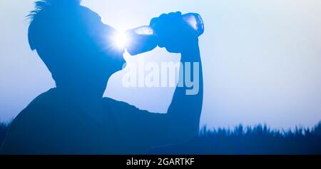 Silhouette eines Athleten mit einer Flasche Wasser. Stockfoto