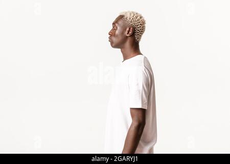 Profil von ernst aussehenden afroamerikanischen blonden Mann, der links, stehend über weißem Hintergrund Stockfoto