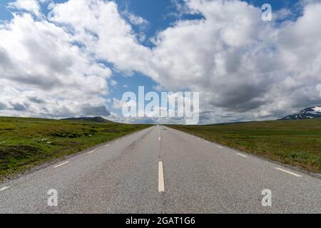 Ein niedriger Winkel auf eine gepflasterte Autobahn, die direkt zum Horizont in einer wilden Tundralandschaft führt Stockfoto