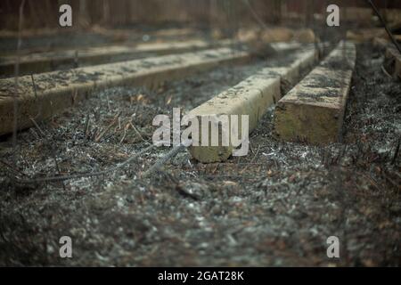 Betonbalken auf dem Boden. Nach einem Brand Materialien bauen. Bleibt auf der verbrannten Erde. Betonblöcke. Stockfoto