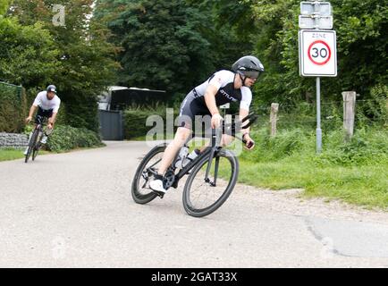 Maastricht, Niederlande. August 2021. Marcel Nijsten aus Valkenburg (Niederlande) auf seinem Rennrad beim Ironman 70.3 Maastricht-Limburg Triathlon, gefolgt von Maxim Mahoney aus den USA. Aufgrund des schnell fließenden Wassers in der Maas nach den jüngsten Überschwemmungen wurde der Schwimmabschnitt der Strecke durch einen zusätzlichen Laufabschnitt ersetzt, was den Triathlon zu einem Run-Bike-Run-Event machte. Anna Karpendale/Alamy Live News Stockfoto