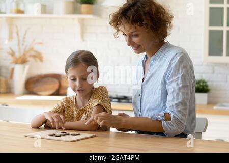 Lächelnde Mutter mit kleiner Tochter, die Spaß hat, Brettspiel spielt Stockfoto