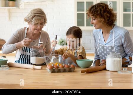 Glückliche drei Generationen von Frauen backen, kochen Teig zusammen Stockfoto