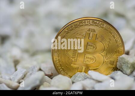 Einzelne goldglänzende Bitcoin-Münze aus Kryprocurrency, die auf einer Kiesfront steht Stockfoto