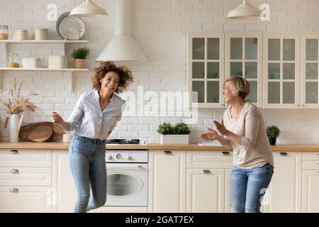 Glückliche Frau mit reifer Mutter tanzt in der modernen Küche zusammen Stockfoto