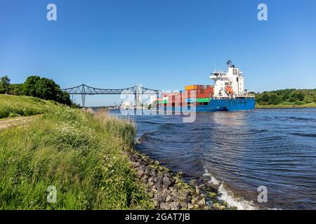 Containerschiff im Nord-Ostsee-Kanal mit der berühmten Rendsburg-Hochbrücke im Hintergrund Stockfoto