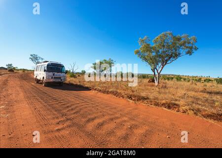 Ein Toyota Coaster Wohnmobil fährt auf einer Wellpappenstraße mit rotem Staub im Outback, Gibb River Road, Kimberley Region, Western Australia, WA, Australien Stockfoto