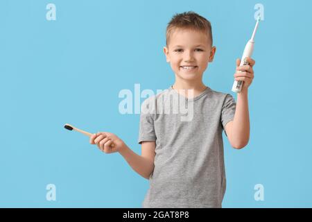 Kleiner Junge mit Zahnbürsten auf farbigem Hintergrund Stockfoto